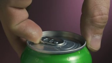 Adamın biri bulanık bir arka planda yeşil bira kutusu açıyor. Çalkalanmış bir kavanozdan beyaz köpüklü bir çeşme dökülüyor. Metal kavanozda bira. Ağır çekim. Kapat..