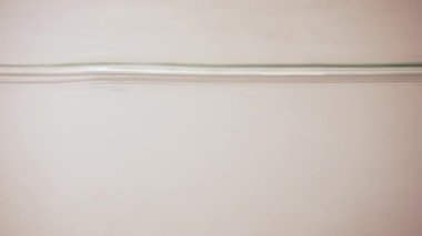 Su yüzeyi dokusu. Beyaz kumun üzerinden aceleyle akmayan temiz su dalgaları geçiyor. Ağır çekim. Kapat..