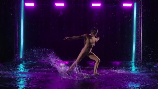 Charmante junge Frau tanzt modernen Contest auf der Wasseroberfläche im Regen. Eine sanfte Tänzerin liegt auf dem Wasser, bewegt ihren flexiblen Körper anmutig und sorgt so für jede Menge Spritzer. Zeitlupe. — Stockvideo