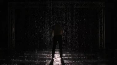 Modern bale, tefekkür, çağdaş sahne ışıklarının altında çıplak vücutlu bir adam tarafından sahneleniyor. Dansçının silueti, yağmur damlalarının arasında ağır çekimde hareket ediyor..