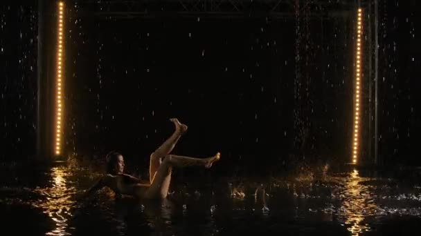 Emocional dramático contemporáneo bajo la lluvia realizado por la bailarina húmeda, medio desnuda. Silueta de mujer acostada en la superficie del agua y creando salpicaduras a su alrededor. Pasión, emociones, sentimientos. Movimiento lento. — Vídeos de Stock