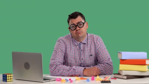 Un homme fatigué est assis à son bureau devant un ordinateur portable, bâillant, couvrant sa bouche de sa paume. Portrait d'un homme avec des lunettes en studio sur un écran vert. Au ralenti. Gros plan. — Video