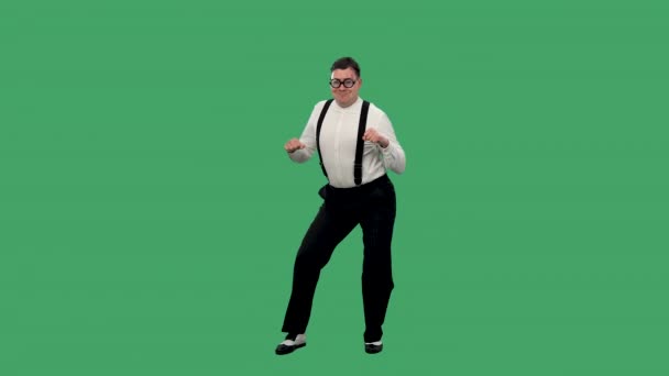 Portrait of a contented man dancing incendiaryly. A man in glasses with thick lenses, a white shirt with suspenders is dancing in the studio on a green screen. Slow motion. — Stock Video