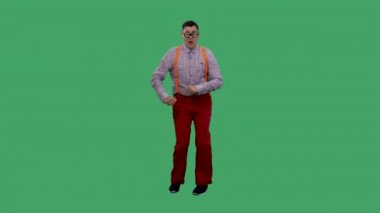 Adam dans eder, şarkı söyler, kaşlarını düzeltir, flört eder. Kalın camlı gözlüklü, ekose gömlekli, turuncu askılı yeşil ekranlı bir adamın portresi. Yavaş çekim.