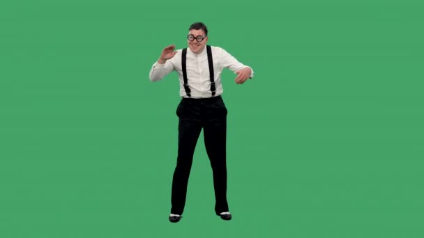 Portret van een tevreden man die danst en klapt in zijn handen. Een man in een wit shirt met bretels en bril met dikke lenzen poseert in de studio op een groen scherm. Langzame beweging. — Stockvideo