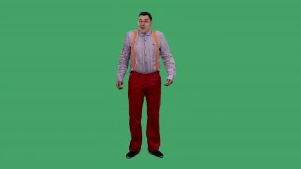 A surprised shocked man with an impressed expression says, oh my god. Portrait of a man in glasses, in a plaid shirt with orange suspenders in the studio on a green screen. Slow motion. — Stock Video