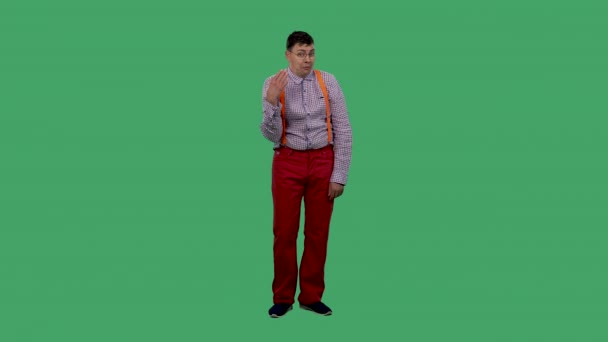 The man waves a hand at his face and exhales in relief. Portrait of a man in glasses, in a plaid shirt with orange suspenders in the studio on a green screen. Slow motion. — Stock Video