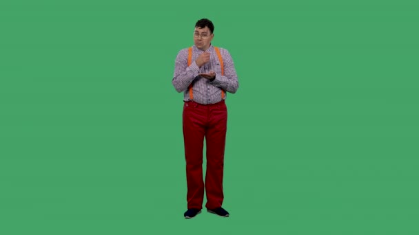 Portrét muže, jak pláče a sbírá slzy v dlani. Muž v brýlích, v kostkované košili s oranžovými podvazky ve studiu na zelené obrazovce. Zpomalený pohyb. — Stock video