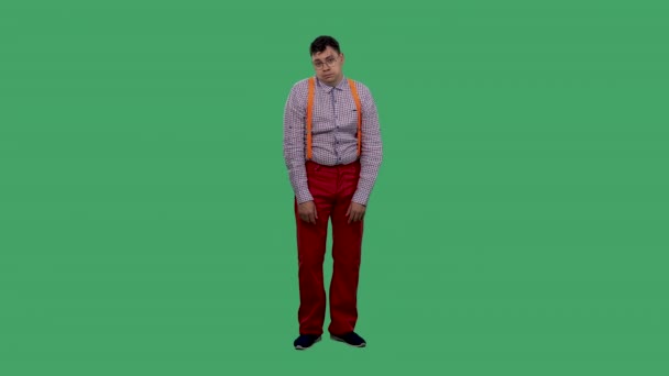 The tired, displeased man sighs heavily and shrugs. Portrait of a man in glasses, in a plaid shirt with orange suspenders in the studio on a green screen. Slow motion. — Stock Video