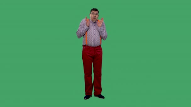 Mannen, rädd, räcker upp handen och försvarar sig. Porträtt av en man i glasögon, i en skjorta med orange hängslen i studion på en grön skärm. Långsamma rörelser. — Stockvideo