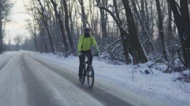 Kışın bisiklet sürmek. Bisikletçi kaygan asfalt bir yolda gidiyor. Kask takan ve sıcak spor kıyafetleri giyen bir adam soğuk bir günde karlı bir ormanda ata biniyor. Karlı ormanda zorlu bir yürüyüş. Yavaş çekim.