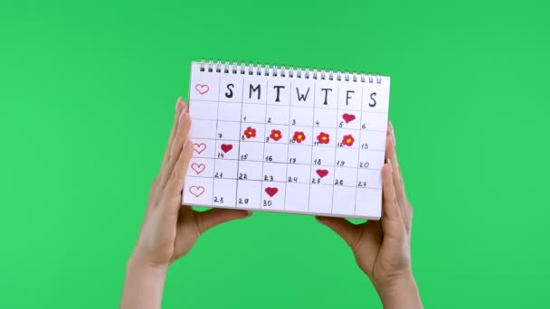 As mãos femininas seguram um calendário de períodos de mulheres para verificar dias de menstruação, isolado no estúdio tela verde croma fundo chave. Conceito ginecológico de saúde médica. Movimento lento. Fechar. — Vídeo de Stock