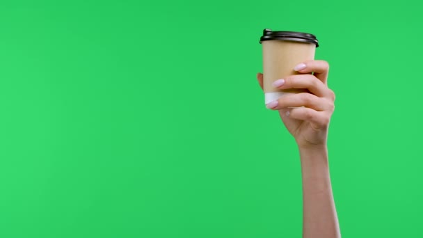 Una mano de mujer sostiene una taza de papel con café, la otra mano señala el dedo índice al café y muestra el pulgar hacia abajo. Primer plano de la taza de café, las manos de mujer en la pantalla verde en el estudio. Movimiento lento. — Vídeo de stock