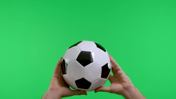 Male hands holding a classic black and white soccer ball, isolated on studio green screen of key chroma. The concept of sports, football. Slow motion. Close up. — Stock Video