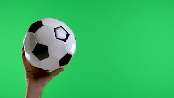 Чоловіча рука вказує з індексним пальцем і показує великий палець до другої руки тримає класичний чорно-білий футбольний м'яч на зеленому екрані студії. Повільний рух. крупним планом . — стокове відео