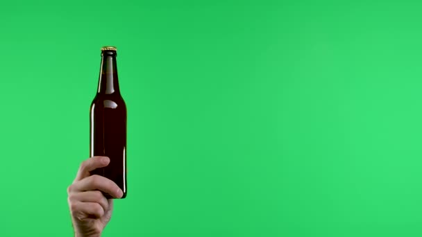 A mans hand holds a dark brown bottle of beer or lemonade, while the other hand waves his index finger no, no, no. Close up of a mans hand on a green screen in the studio. Slow motion. — Stock Video