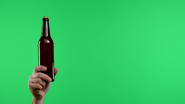 Las manos masculinas sostienen una botella de cerveza o limonada de color marrón oscuro, luego los brazos se doblan para mostrar el gesto de no, detener. Primer plano de una mano de hombre y una botella marrón en una pantalla verde en el estudio. Movimiento lento — Vídeo de stock