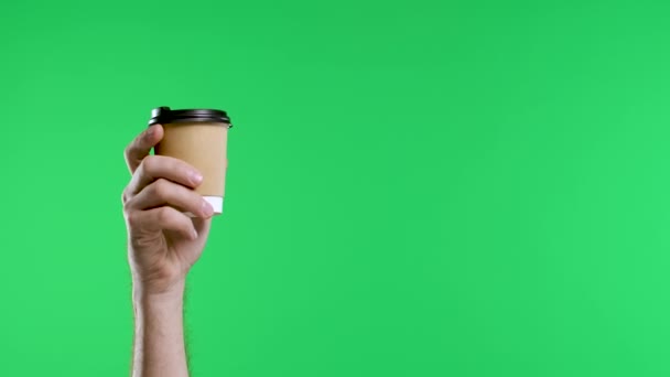 La mano masculina señala con el dedo índice a la otra mano sosteniendo una taza de papel de café y muestra el pulgar hacia arriba. Primer plano de una mano de hombre sobre un fondo de tecla croma pantalla verde. Movimiento lento. — Vídeo de stock