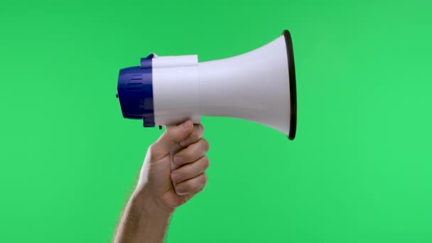 Een mannelijke hand heft een witte megafoon tegen een groene scherm chroma key achtergrond. Luidspreker voor sociaal spreken in een opgeheven hand. Een speciale aankondiging, reclame. Langzame beweging. Sluiten.. — Stockvideo