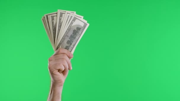 Male hands hold a bundle of dollar bills and a vintage watch on a chain against a green screen chroma key background. The concept of money payments, savings. Slow motion. Close up. — Stock Video