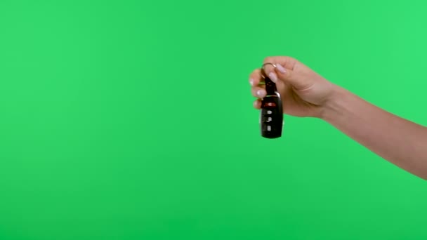 Ženská ruka držící ovladač auta, strčí klíčky od auta do mužské dlaně. Zámek dveří auta s dálkovým ovládáním a barevným klíčem zelené pozadí obrazovky. Kupte si koncepci pronájmu auta. Zpomal. Zavřít. — Stock video