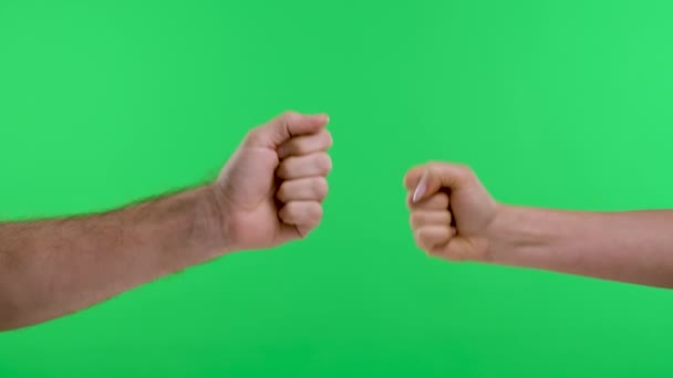 Una mujer, un hombre están jugando tijeras de papel de roca contra el fondo de la pantalla verde. Cerca de las manos masculinas y femeninas, el hombre pone su mano sobre las manos de las mujeres, mostrando el pulgar hacia arriba. Movimiento lento — Vídeos de Stock