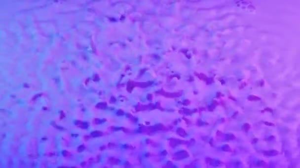Starke Vibrationen heben die Milch mit rosa-blauer Tönung nach oben. Rasch wechselnde Schwingungswellenstrukturen erzeugen Resonanz und Tropfen werden an der Oberfläche der Milchflüssigkeit aufgehängt. Zeitlupe. Nahaufnahme. — Stockvideo
