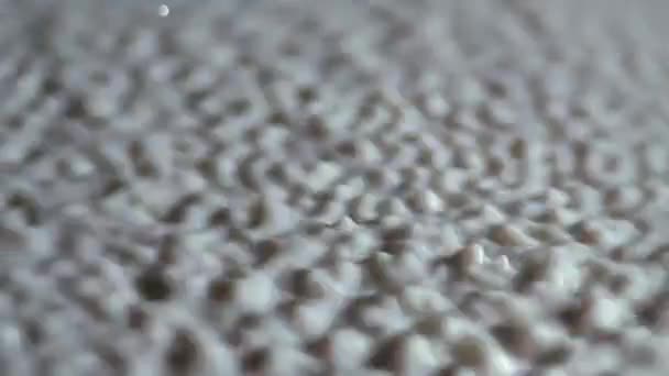 Macro shot de vibrar gotas esféricas de leite branco. A vibração forte levanta gotas líquido leitoso para cima. Movimento intenso de salpicos e gotas ao vibrar a superfície do leite. Movimento lento. Fechar. — Vídeo de Stock