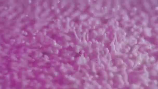 Makro ujęcie wibrujących kulistych kropli fioletowego mleka. Silne wibracje podnoszą krople lepkiej mlecznej cieczy w górę. Intensywny ruch rozprysków i kropli podczas wibracji powierzchni mleka. Zwolniony ruch. — Wideo stockowe