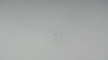 Düz beyaz süt yüzeyi hoparlörün frekansına titreşmeye başlar. Yapışkan süt sıvısı, dalgalar, daireler ve damlalar. Ağır çekim. Kapat..