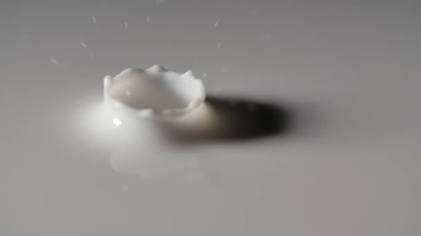 Een druppel melk valt op het oppervlak van de witte vloeistof, waardoor een rimpelgolf ontstaat en een prachtige kroonplons ontstaat. Vallende druppelmelk met rimpels en cirkels, slow motion. Sluiten.. — Stockvideo