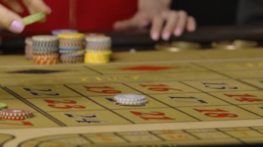 Kumarhanede bahis oynayan erkekler ve kadınlar. Kumarbazlar oyun çiplerini rulet masasına kırmızı ve siyah numaralara koyarlar. Kumar kulübündeki göz kamaştırıcı parti. Eller yukarı. Yavaş çekim hazır, 4K 59.94fps 'de..