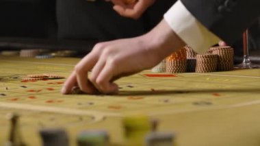 Kumarhanede bahis oynayan erkekler ve kadınlar. Kumarbazlar oyun çiplerini rulet masasına kırmızı ve siyah numaralara koyarlar. Ellerini farklı bir alan derinliğinde kapat. Yavaş çekim hazır, 4K 59.94fps 'de..