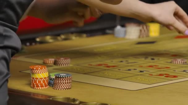 Men and women betting in casino. Gamblers lay out game chips on roulette table. Unrecognizable people drinking champagne, enjoying game. Hands close up. Slow motion ready, 4K at 59.94fps. — Stock Video