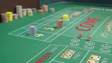 Kumarhanedeki yeşil barbut masasının yanına çip koyun. Bahisler yatırıldı. Erkek eli zarları atıyor. Farklı bir alan derinliği. Yavaş çekim.