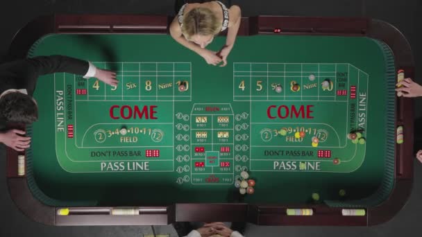 Top view két férfi és egy nő játszik kocka, miközben ül egy asztalnál egy kaszinóban. A játékosok zsetonnal fogadnak. A nő dobja a kockát és nyer. Lassú mozgás kész, 4K 59.94fps-on.. — Stock videók