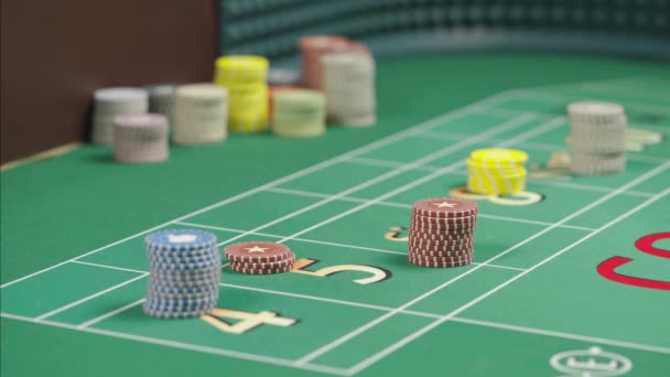 Close-up van een groene craps goktafel in een casino met geplaatste chips. Weddenschappen zijn geplaatst. De geworpen dobbelstenen vallen op de speeltafel. Verschillende scherptediepte. Langzame beweging. — Stockvideo