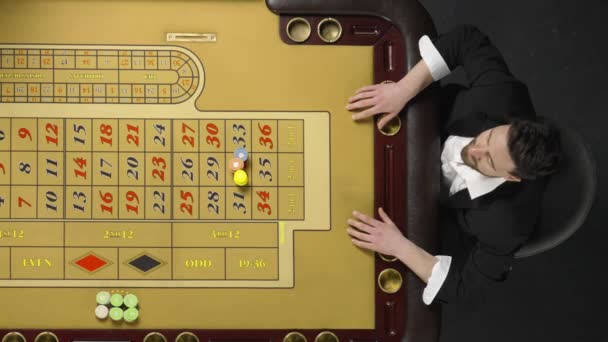 Top view of bearded man sitting at roulette table in casino. Player bets all his chips and wins. Happy gentleman celebrates victory, scattering chips. Money rain. Slow motion ready, 4K at 59.94fps. — Stock Video