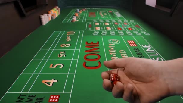 Een mannelijke hand gooit dobbelstenen op een groene craps tafel in een casino. Close-up van een speeltafel met geplaatste chips. Het concept van gokken. Langzame beweging. — Stockvideo