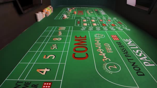 Zamknij zielony stół do gry w kości w kasynie. Czerwone kości spadają na powierzchnię stołu z żetonami na miejscu. Koncepcja hazardu. Widok z wnętrza stołu do gry. Zwolniony ruch. — Wideo stockowe