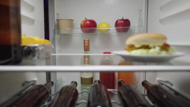 Fröhliche Frau öffnet die Kühlschranktür in der Nacht isst Chips und nimmt glücklich eine Flasche Bier heraus. Blick aus dem Inneren des Küchenkühlschranks. Aus nächster Nähe. Zeitlupe bereit 59.94fps. — Stockvideo