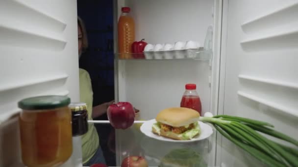 Junge Frau öffnet nachts die Kühlschranktür und nimmt Apfel statt Burger. Gesunder Lebensstil, gesunde Ernährung. Blick von innen auf den funktionierenden Kühlschrank. Aus nächster Nähe. Zeitlupe bereit 59.94fps. — Stockvideo