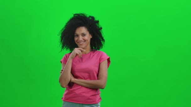 Retrato de una joven afroamericana mirando coqueta a la cámara y haciendo gestos, llámame. Mujer negra con el pelo rizado posa en pantalla verde en el estudio. De cerca. Cámara lenta lista 59.97fps. — Vídeo de stock