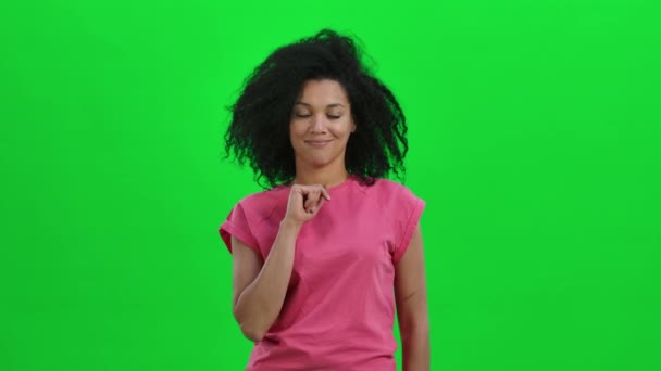 Портрет молодої афроамериканки, що щось говорить і робить тихий жест, таємницю. Чорна жінка з хвилястим волоссям на зеленому екрані в студії. Закрийся. Повільний рух готовий до 59.97fps. — стокове відео