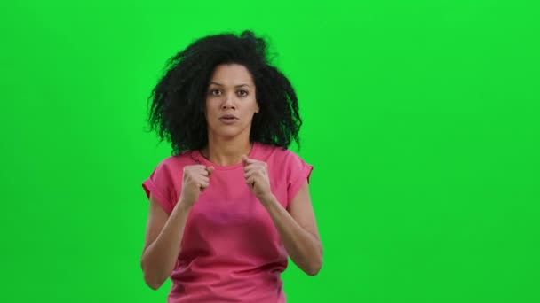 Retrato de una joven afroamericana mirando a la cámara con emoción y anticipación, luego muy molesta. Mujer negra con pelo rizado posa en la pantalla verde. De cerca. Cámara lenta lista 59.97fps. — Vídeo de stock