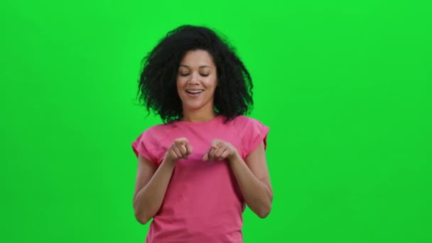 Ritratto di giovane afroamericana che sorride e mostra il cuore con le dita poi soffia bacio. Donna nera con capelli ricci posa sullo schermo verde in studio. Chiudete. Rallentatore pronto 59.97 fps. — Video Stock