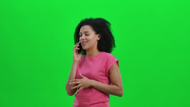 Retrato de una joven afroamericana hablando por teléfono móvil y regocijándose. Mujer negra con el pelo rizado posa en la pantalla verde en el estudio. De cerca. Cámara lenta lista 59.97fps. — Vídeo de stock