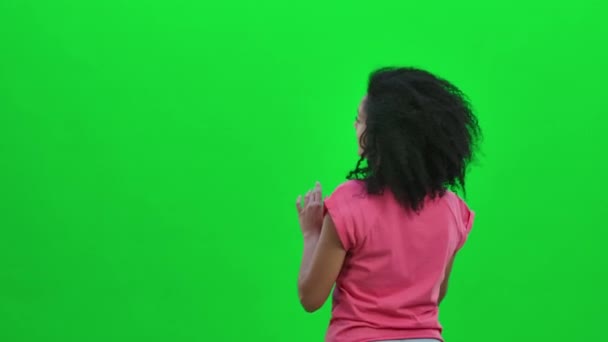 Rückansicht einer jungen Afroamerikanerin, die etwas erwägt und auswählt. Schwarze Frau mit lockigem Haar posiert auf grünem Bildschirm im Studio. Aus nächster Nähe. Zeitlupe bereit 59.97fps. — Stockvideo