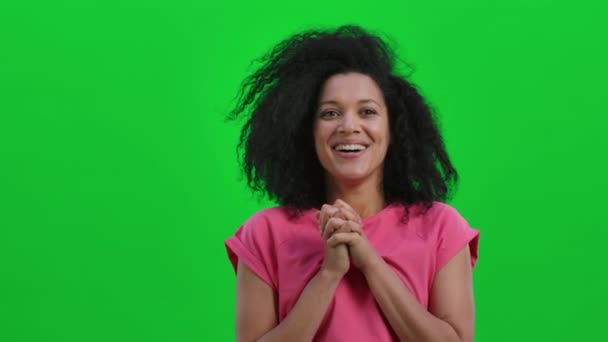 Retrato de una joven mujer afroamericana sonriente mirando a la cámara con alegría y deleite. Mujer negra con pelo rizado posa en la pantalla verde. De cerca. Cámara lenta lista 59.97fps. — Vídeo de stock