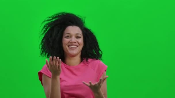 Retrato de joven sonriente mujer afroamericana ríe alegremente. Mujer negra con el pelo rizado posa en la pantalla verde en el estudio. De cerca. Cámara lenta lista 59.97fps. — Vídeo de stock